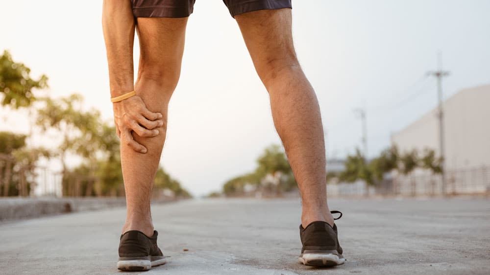 Man grabbing leg due to peripheral artery disease