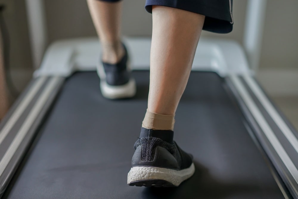 woman wearing athletic shoes, compression socks walking on treadmill