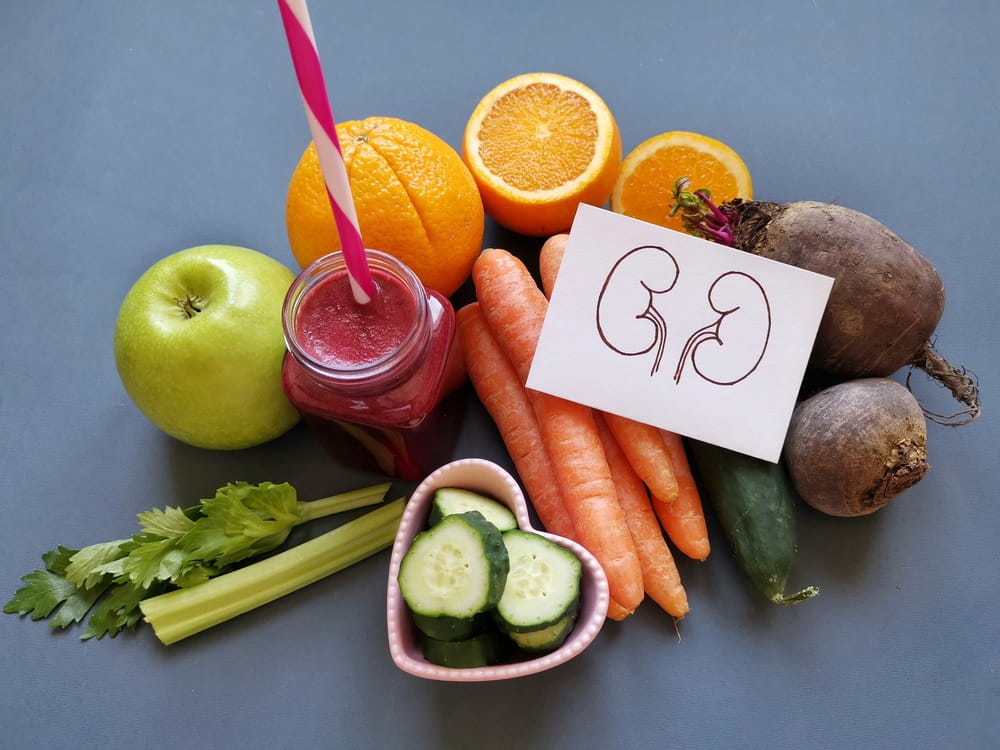 medly of vegetables, fruits and juices that support kidney health with cartoon drawing of kidneys