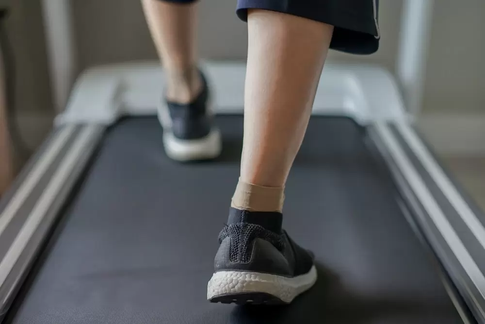 woman wearing athletic shoes, compression socks walking on treadmill