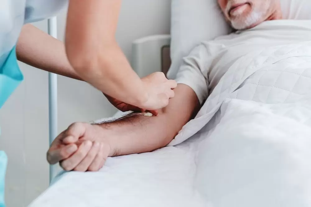 white nurse inserting dialysis needle into white man's arm