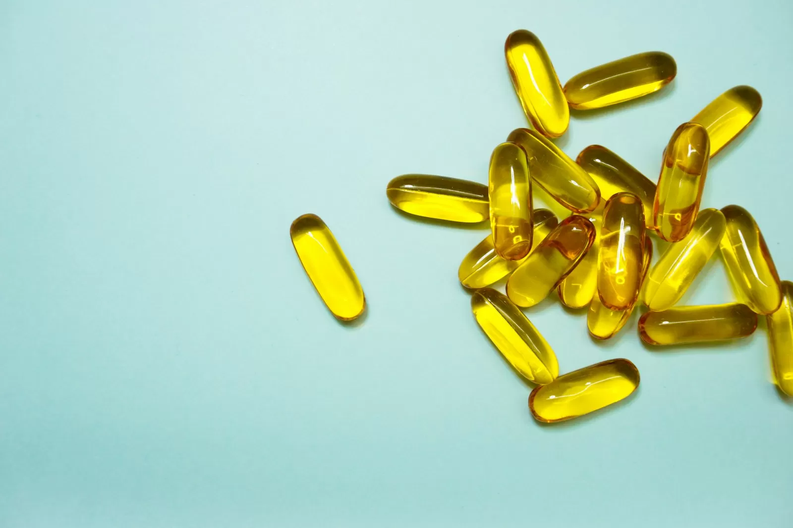 Vitamin softgel capsules on a light blue surface